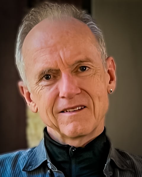 a close up of a person wearing a black shirt. Headshot of executive integral coach, John Dunham, founder and principal coach at Bring All of You, LLC.